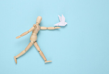 Wooden puppet with Origami dove on blue background