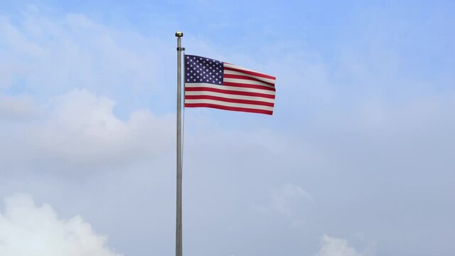 American flag waving in the wind with blue sky and clouds. USA banner blowing, soft and smooth silk. Cloth fabric texture ensign background. Use it for national day and country occasions concept.-Dan