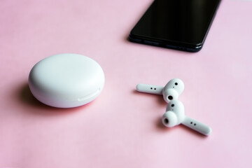 Wireless headphone and smartphone on pink background