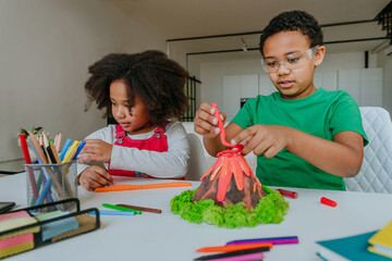 Children making DIY volcano model from kids play clay