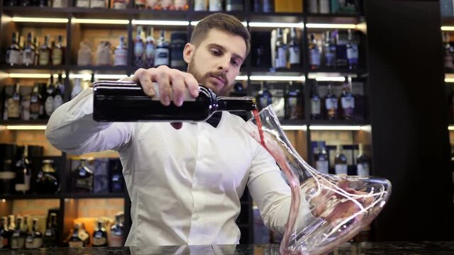 Decantation. Sommelier pouring wine to the decanter in the wine cellar