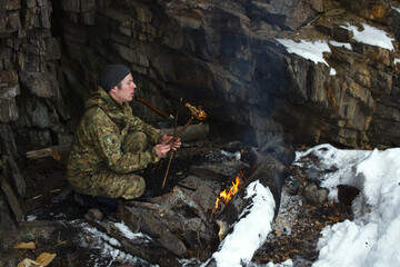 Traveller checks the readiness of the meat fried over an open fire.