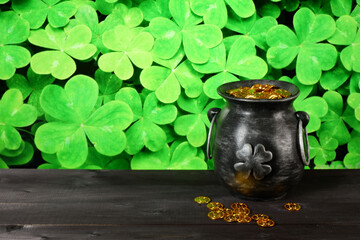 Cast iron pot, decorated by four-petal lucky shamrock leaf, full of leprechaun gold treasure on...