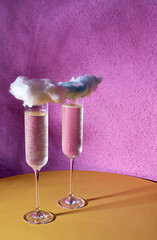 champagne in a glass decorated with a cloud on a pink background.
