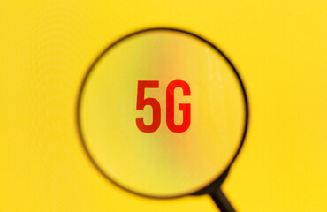 Text 5G on yellow screen through magnifying glass.