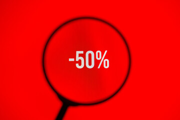 Word sale -50% on red screen through magnifying glass.