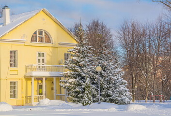 Winter landscape with a beautiful old mansion and snow-covered fir trees by the porch