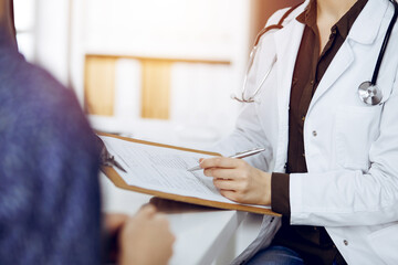 Obraz premium Doctor and patient discussing current health examination while sitting in sunny clinic. Medicine concept