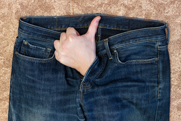 A man's hand, with his thumb raised, protrudes from the fly of his jeans. Treatment of erectile dysfunction and sexual disorders.