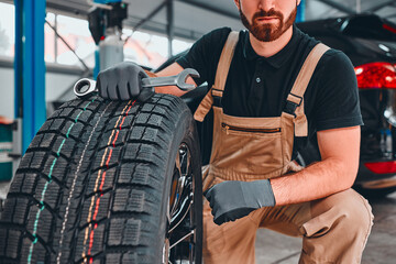 Fototapeta premium Mechanic holding car tire at garage.