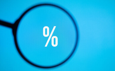 % sale symbol on blue screen through magnifying glass.