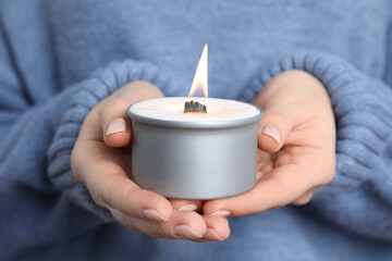 Woman holding burning candle with wooden wick, closeup