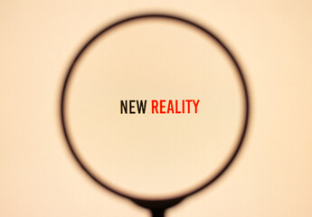 Tex new reality on yellow screen through magnifying glass.
