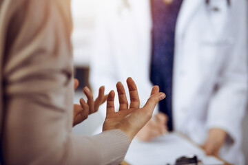 Doctor and patient discussing current health examination while sitting in sunny clinic. Medicine...