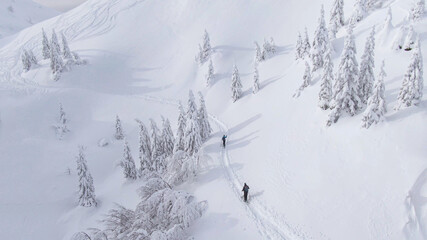 AERIAL: Spectacular flying view of wintry landscape surrounding two ski tourers.