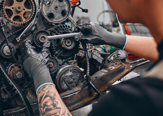 Fototapeta na wymiar A car mechanic repairs a car engine in his repair shop.