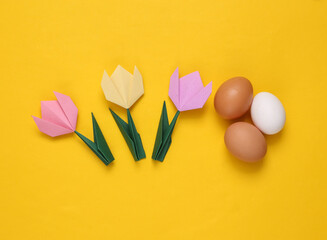 Origami tulips and eggs on yellow background. Spring, easter concept