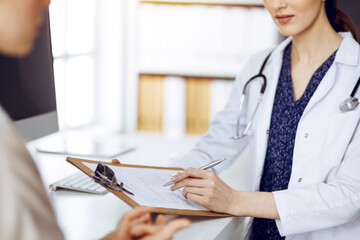 Doctor and patient discussing current health examination while sitting in sunny clinic. Medicine...
