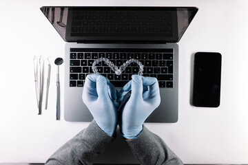 View from above of doctor's hands with heart-shaped dental aligners