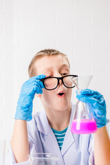 A schoolboy studies multi-colored substances in test tubes, conducts experiments - a portrait on a white background. Concept for the study of coronavirus in the laboratory