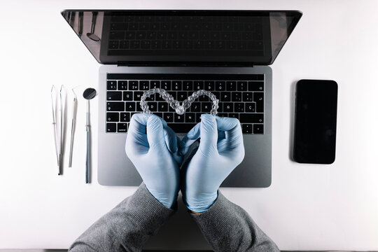 View from above of doctor's hands with heart-shaped dental aligners