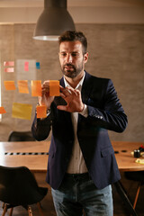 Businessman in conference room use sticky notes on glass wall. Handsome businessman making a business plan