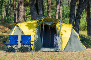camping and two chairs in a picturesque place among pine trees