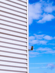 surveillance camera on wall against blue sky