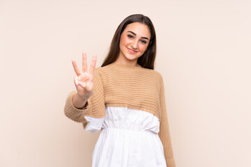 Young caucasian woman isolated on beige background happy and counting three with fingers