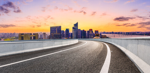 Asphalt road and modern city skyline with buildings in Hangzhou at sunset.