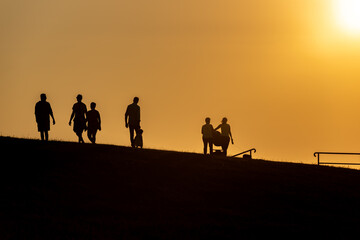 Fototapeta na wymiar Tourists in the evening light on the dike in Cuxhaven