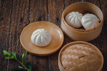 Steamed pork buns on wooden plate and bamboo steamer, Chinese dim sum .