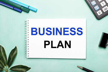 BUSINESS PLAN is written on a white sheet on a blue background near the stationery and the Scheffler sheet. Call to action. Motivational concept