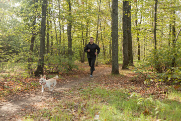 Sport Man runningon in forest with pet. Healthy active man jogging with dog