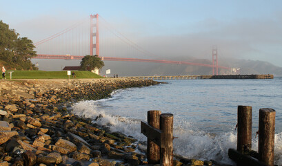Waves crash on the shore with the Golden Gate Bridge in the Background.