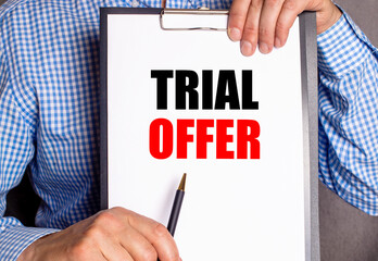The man points with a pen to the text TRIAL OFFER on a white sheet.