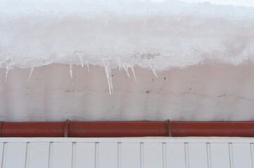 The high roof of a building with a large snowdrift. Danger of snow falling from the roof