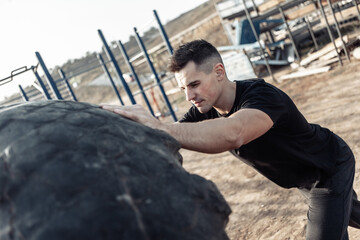 Active fitness man lifts heavy wheels on an outdoor training ground. Cross training. Healthy lifestyle