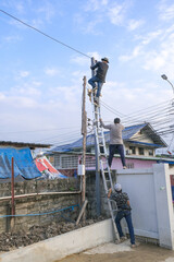 Electrician male Team climbing pole for install wire power cable . professional technician worker setting connect electric metal box