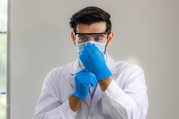 Close up male doctor, researcher, scientist wearing eye protection glasses, white suit, glove and...