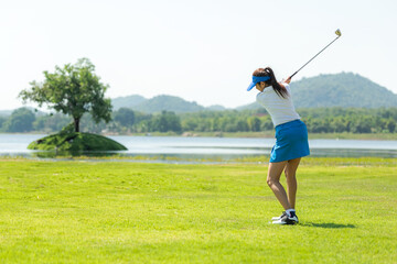 Golfer sport course golf ball fairway. People lifestyle woman playing game golf and hitting go on green grass river and mountain background.