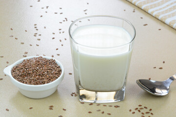 Flaxseed milk in a glass cup with flaxseeds in a bowl