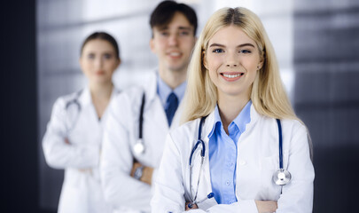 Group of three young doctors standing as a team with arms crossed in modern clinic and ready to help patients. Medicine concept