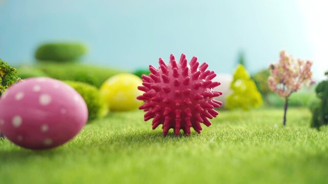 Hand laying coronavirus shaped ball on grass in easter fairytale fictional macrocosm