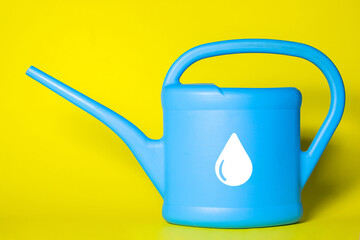 Watering can with water on a yellow background. Water drop sign. Irrigation with environmentally friendly water. Caring for the environment