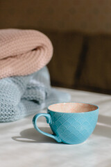 Gray and pink knitted blankets and a blue cup on a white background. Seasonal time change, daylight saving time concept. Vertical image.