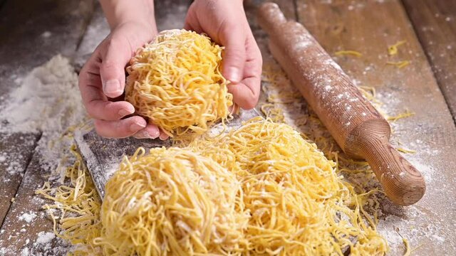Tagliatelle pasta is thin. Traditional Italian named Angel Hair (capellini d'angels). Woman cooking Italian egg pasta, homemade and fresh in flour on a cutting table. vertical video for social media