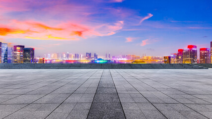 Empty square floor and modern city skyline with buildings in Hangzhou at night.