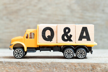 Toy truck hold alphabet letter block in word Q&A (Abbreviation of question and answer) on wood...