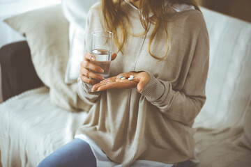 Close-up woman holding pills time to take medications, cure for headache, high blood pressure or cholesterol level remedy pain killer drugs. Stay at home concept during Coronavirus pandemic and self